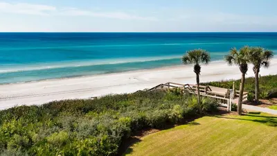 a beach with a bench and palm trees and the ocean at Palms C11 in Santa Rosa Beach