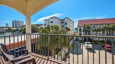 a balcony with a chair and a street with buildings at Palms D7 in Santa Rosa Beach