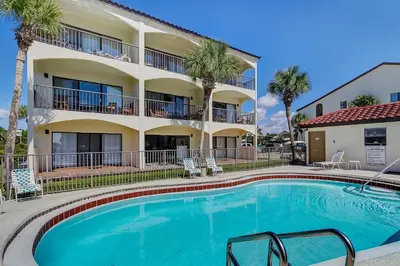 a swimming pool in front of a building with palm trees at Palms D7 in Santa Rosa Beach