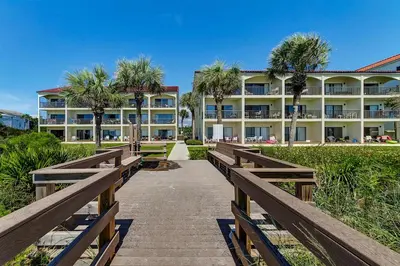 a boardwalk leading to a resort with palm trees at Palms D7 in Santa Rosa Beach