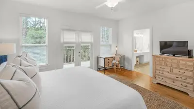 a white bedroom with a bed and a television at Grateful By the Sea in Santa Rosa Beach