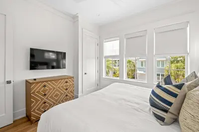 a white bedroom with a bed and a flat screen tv at Maison de Joie in Inlet Beach