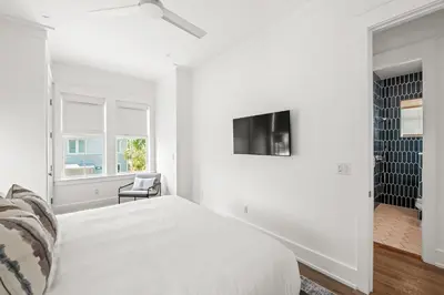 a white bedroom with a bed and a tv at Maison de Joie in Inlet Beach
