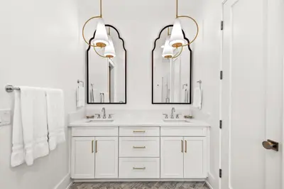 a white bathroom with two sinks and two mirrors at Maison de Joie in Inlet Beach