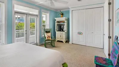 a bedroom with a white bed and a white door at Pink Flamingo in Panama City Beach