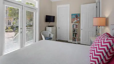 a bedroom with a bed and a window and a tv at Pink Flamingo in Panama City Beach