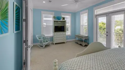a bedroom with a bed and a tv and windows at Pink Flamingo in Panama City Beach