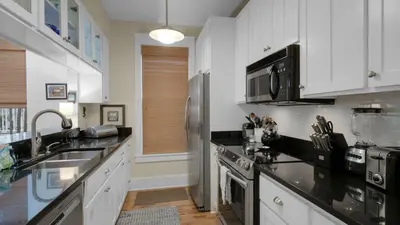 a kitchen with white cabinets and black counter tops at Quietude in Santa Rosa Beach