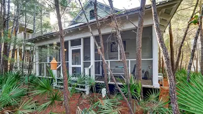 a white house with trees and plants in front of it at Quietude in Santa Rosa Beach