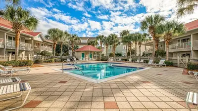 a swimming pool in a courtyard with palm trees at Rollin Tide C2 - Seaglass Sands in Santa Rosa Beach