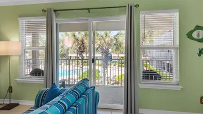 a living room with blue chairs and windows at Rollin Tide C8 in Santa Rosa Beach
