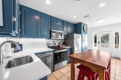 a kitchen with blue cabinets and a wooden table at Leo's Hideaway in Panama City Beach