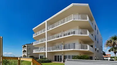 an apartment building with white balconies and palm trees at Sago Sands 402 in Santa Rosa Beach