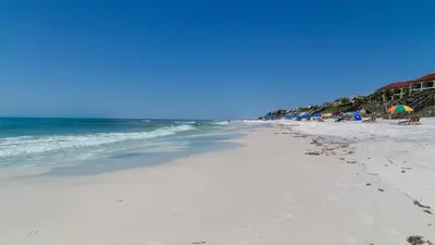 a beach with people and umbrellas and the ocean at Sago Sands 402 in Santa Rosa Beach