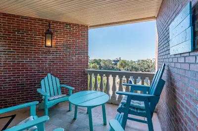 a patio with blue chairs and a table on a brick wall at Village of South Walton 314D - Serenity in Rosemary Beach