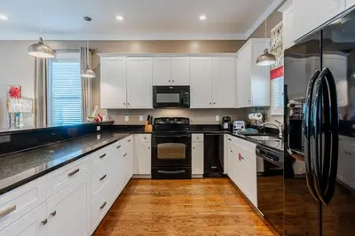 a kitchen with white cabinets and black appliances at Lifeguard Loop in Rosemary Beach