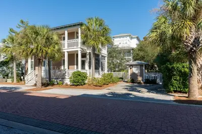 a house with palm trees in front of a street at Lifeguard Loop in Rosemary Beach