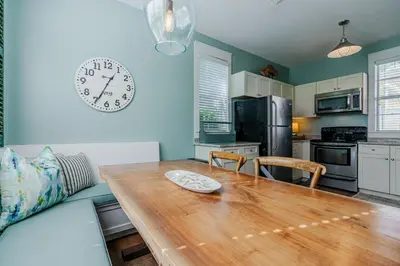 a kitchen with a wooden table and a clock on the wall at Salty Paws Bungalow in Santa Rosa Beach