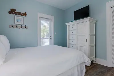a bedroom with a white bed and a tv on a cabinet at Salty Paws Bungalow in Santa Rosa Beach