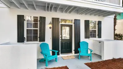 two blue chairs sitting on the front porch of a house at Salty Paws Bungalow in Santa Rosa Beach