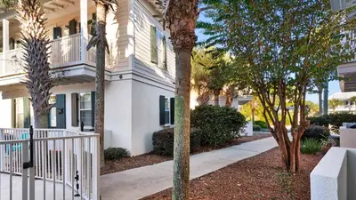 a house with a fence and trees in front of it at Salty Paws Bungalow in Santa Rosa Beach
