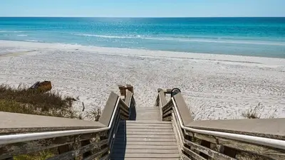 a staircase leading to a beach with the ocean at Salty Paws Bungalow in Santa Rosa Beach