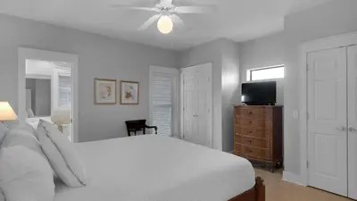 a white bedroom with a bed and a flat screen tv at Seaview II #200 in Santa Rosa Beach
