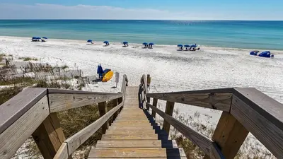 a wooden staircase leading to a beach with umbrellas at Seaview II #200 in Santa Rosa Beach