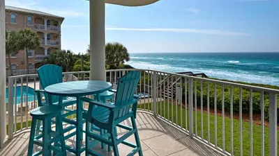 a table and chairs on a balcony with the ocean at Tranquillity 220 in Panama City Beach