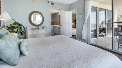 a bedroom with a large bed and a mirror at Tranquillity 220 in Panama City Beach