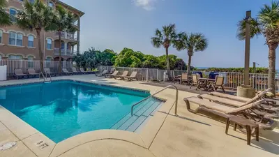 a swimming pool with lounge chairs and a building at Tranquillity 220 in Panama City Beach