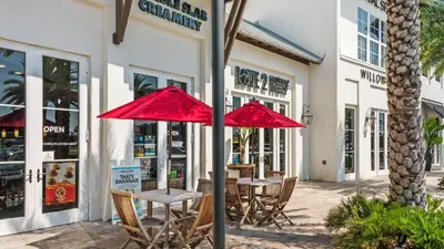 two tables with red umbrellas in front of a store at Tranquillity 220 in Panama City Beach