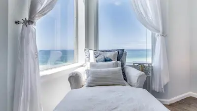 a bedroom with a bed and a window with the ocean at Tranquillity 220 in Panama City Beach