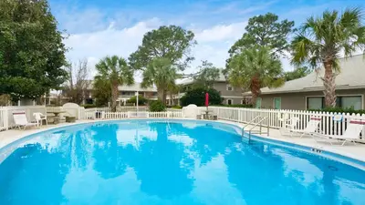 a large blue swimming pool with chairs and trees at Beachwood Villas 3A in Santa Rosa Beach