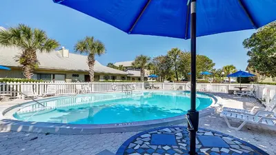 a swimming pool with an umbrella and chairs and tables at Beachwood Villas 3A in Santa Rosa Beach