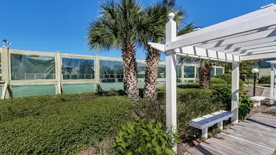 a white pergola and a bench in front of a building at Beachwood Villas 3H in Santa Rosa Beach