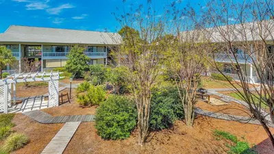 an exterior view of a building with trees and bushes at Beachwood Villas 7F in Santa Rosa Beach