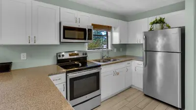 a kitchen with white cabinets and a stainless steel refrigerator at Beachwood Villas 9B in Santa Rosa Beach