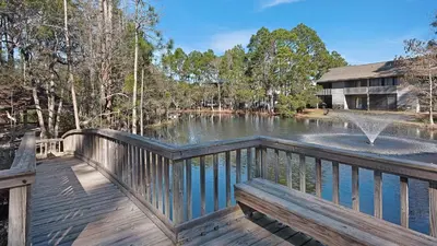 a wooden deck with a fountain and a pond at Crow's Nest in Santa Rosa Beach