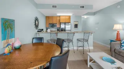 a dining room and kitchen with a wooden table and chairs at Cassine Station 302 in Santa Rosa Beach