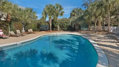 a large blue swimming pool in a yard with palm trees at Cassine Station 302 in Santa Rosa Beach