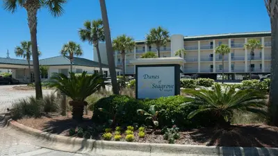 a sign in front of a building with palm trees at Dunes Of Seagrove 201B in Santa Rosa Beach