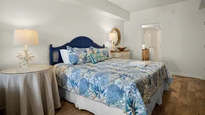 a bedroom with a blue and white bed with a table at Dunes Of Seagrove 201B in Santa Rosa Beach
