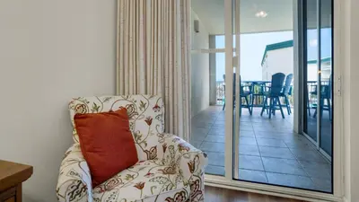 a living room with a chair and a balcony at Dunes Of Seagrove 202C in Santa Rosa Beach