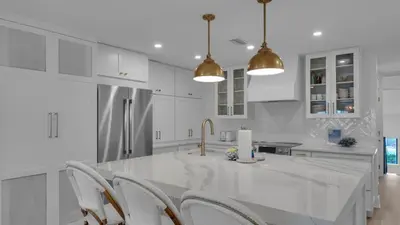 a white kitchen with white cabinets and a counter with chairs at Dune Villas 3B in Santa Rosa Beach