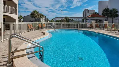 a large blue swimming pool with chairs and a building at Dune Villas 5A in Santa Rosa Beach