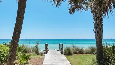 a wooden pathway to the beach with palm trees at Emerald Hill 1 in Santa Rosa Beach