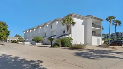 a large white building with palm trees in a parking lot at Emerald Hill 6 in Santa Rosa Beach