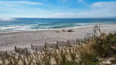 a beach with people sitting on the sand and the ocean at Emerald Hill 9 in Santa Rosa Beach
