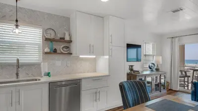 a kitchen with white cabinets and a view of the ocean at Eastern Shores 201 - A Happy Little Condo in Santa Rosa Beach